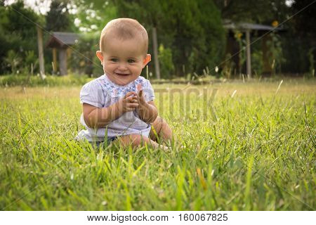 happy young baby child sittng on grass on beautiful summer day in park