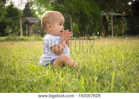 happy young baby child sittng on grass on beautiful summer day in park