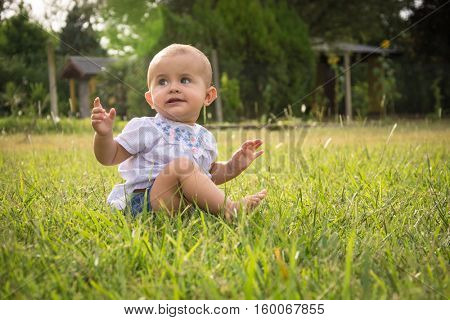 happy young baby child sittng on grass on beautiful summer day in park