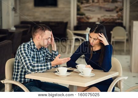 Young couple arguing in a cafe. She's had enough, boyfriend is apologizing. Relationship problems