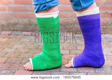 Standing teenage boy with two colorful gypsum legs outdoors