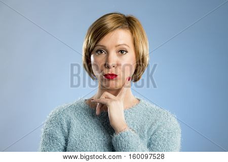 headshot portrait of young beautiful blond woman looking suspicious and grumpy in discontent and tension face expression isolated on blue background