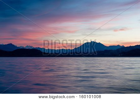Romantic sunset over the lake in the Swiss Alps. Canton Zug. In the background the mountains silhouettes. High Dynamic Range Image