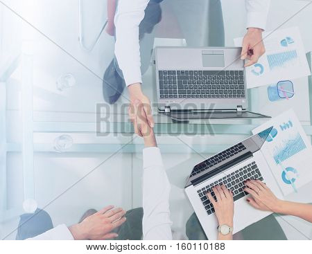 Happy smiling business people shaking hands after a deal in offi