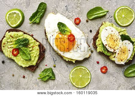Assortment Of Avocado Toasts On A Concrete Or Slate Background.top View.