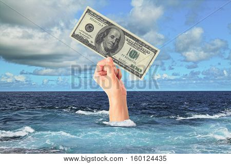 Hand with dollar bill sticking out of ocean. Sky background. Finance and risk concept