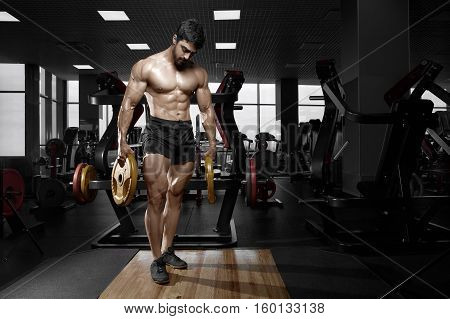 Muscular athletic bodybuilder fitness model posing after exercises in gym