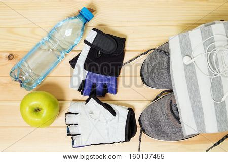 Fitness equipment. Healthy food. Sports equipment. Sportswear. Items, accessories, objects for the sport. Running shoes, sneakers,  gloves, t-shirt, water and an apple.