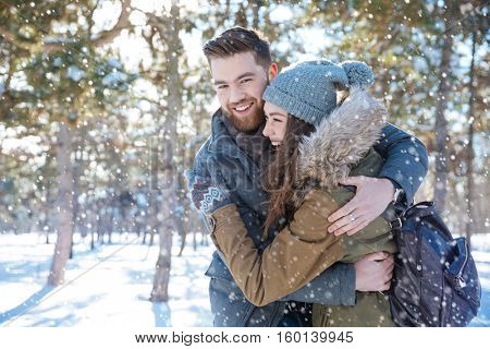 Smiling young couple hugging in winter park