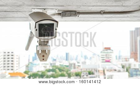 Security equipment concept - Close up indoor CCTV camera surveillance on ceiling of car parking Safety system area control with tower background and copy space