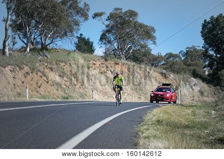 Jindabyne, Snowy Mountains Region, Australia - December 3, 2016: The first L'Etape cycling event held in Australia (by Le Tour de France).  A competitor and race official car in the 2nd race stage.