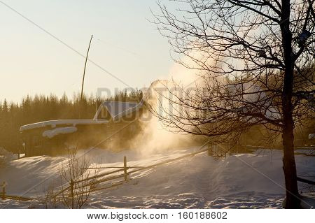 Winter house with a furnace and firewood on sunset and fog