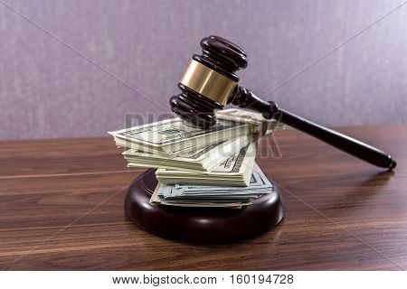 Judge gavel with dollars on wooden table