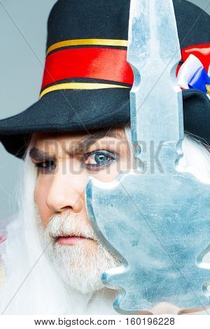 Frown senior man bearded beefeater yeomen warder or male royal guard bodyguard in hat with spear on grey wall