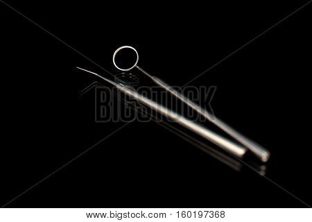 Dental mirror and dental sonde. Image isolated on black background.