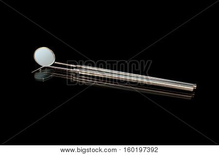Dental mirror and dental sonde. Image isolated on black background.
