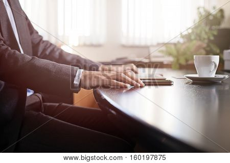 business man hands on a table with tablet phone and cup of coffee in a office