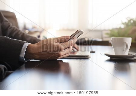 business man hands on a table with tablet phone and cup of coffee in a office