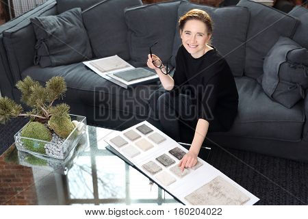 Interior decorating, shopping carpet. Arranging home shopping coverings. Woman chooses carpet for the living roomInterior designer with the probe carpets