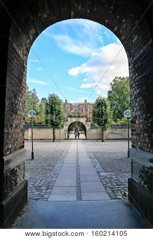 View of the courtyard and a walkway leading to the Danish Jewish Museum Copenhagen Denmark. Tree female tourists standing on a walkway at distance. Danish Jewish Museum at background