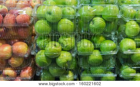 Fresh organic apples in the clear plastic box at the supermarket.