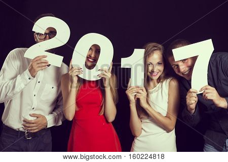 Two beautiful young couples having fun at New Year's Eve Party holding cardboard numbers 2017