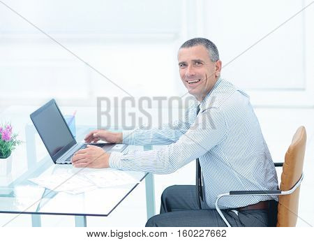 successful smiling businessman working on laptop at Desk in offi