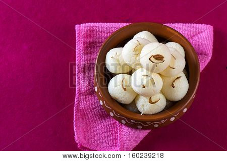 Indian Sweet - Rasgulla, Famous Bengali sweet in clay bowl with napkin on pink background
