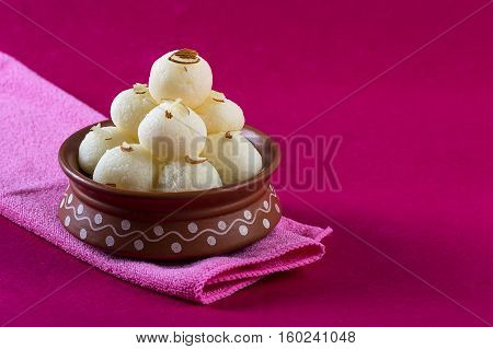 Indian Sweet - Rasgulla, Famous Bengali sweet in clay bowl with napkin on pink background