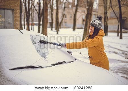 Woman cleaning car windshield of snow winter happy young scraper