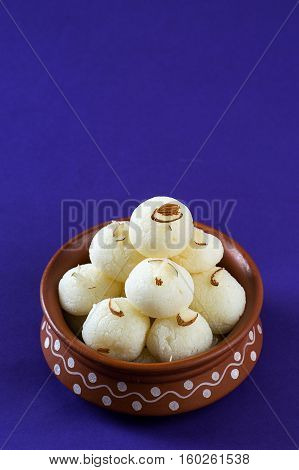 Indian Sweet or Dessert - Rasgulla, Famous Bengali sweet in clay bowl on blue background