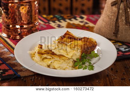 Georgian Dish. Achma With A Sprig Of Parsley On A White Plate