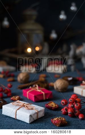 Christmas gifts, rowan, nuts, old lamp and pine branch with cones on dark surface