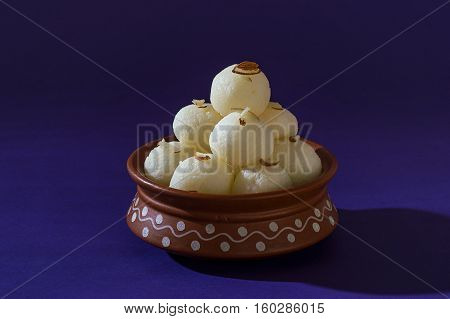 Indian Sweet or Dessert - Rasgulla, Famous Bengali sweet in clay bowl on blue background