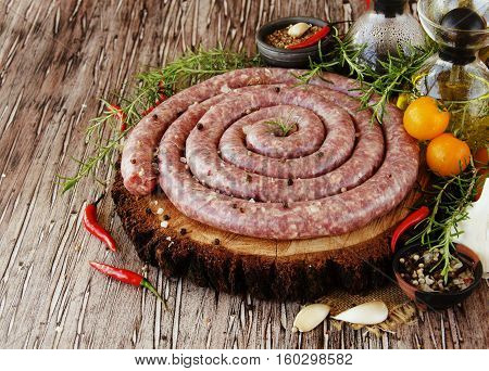 raw beef sausages with rosemary and spices on a wooden table, South African boerewors