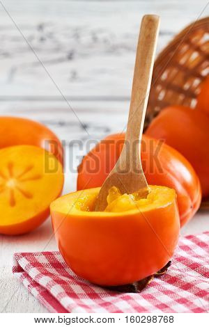 Japanese persimmon (Diospyros kaki) on white rustic wooden background. Copy space