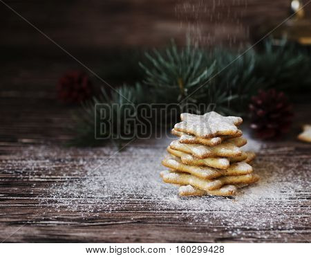 Christmas or new year gingerbread cookies in a Jewish star in a wooden box with cinnamon, almonds, dried slices apelchina and spruce twigs on rustic table, selective focus