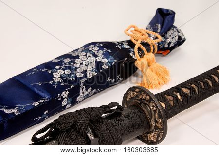 A Japanese sword fitted in a black sheath with a stone-eyed pattern