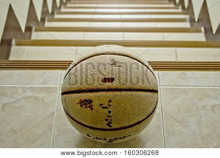 Old basketball on floor and stairway background.