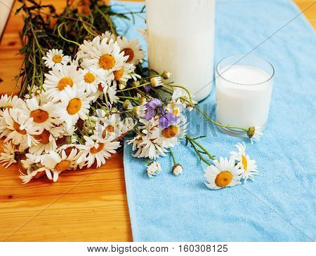 Simply stylish wooden kitchen with bottle of milk and glass on table, summer flowers camomile, healthy foog moring concept noone close up