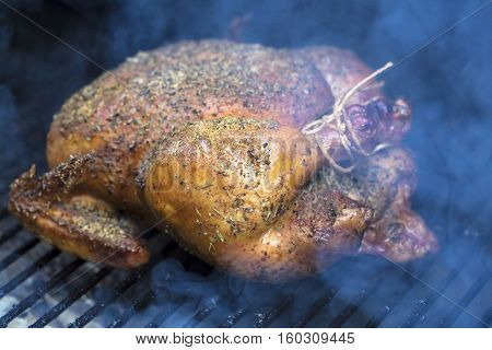Spiced rubbed chicken being grilled in a smoker barbeque