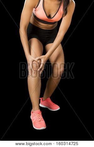 cropped close up view young sport woman holding injured knee suffering pain in ligaments injury or pulled muscle isolated on black background in fitness accident and body health care