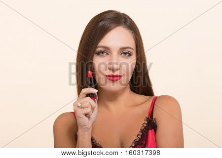 Young model woman showing red lipstick for doing makeup isolated on white, Pretty lady with brown hair looking at camera and smiling.
