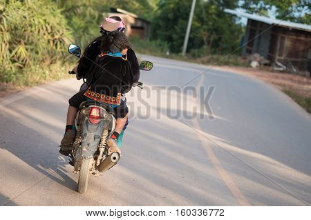 Hmong hill tribe young woman riding motorbike in Hmong village on mountain in Nan province, Thailand.