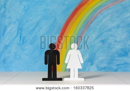 Man and women icons with a rainbow and blue sky to illustrate the concept of male female and gender