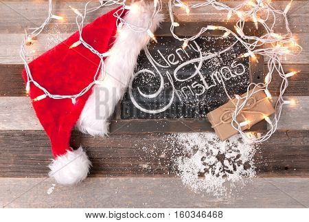 Christmas decoration with place for greeting on chalk blackboard. Santa Claus hat and gift boxes