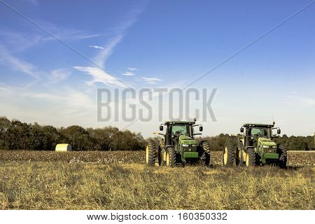 Prattville Alabama USA -- November 5 2016: Two John Deere tractors sitting in front of a harvested cotton field in Alabama.
