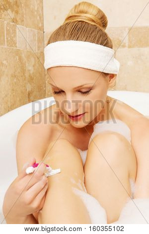 Young caucasian woman shaving legs