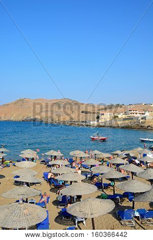 PANORMOS, CRETE - SEPTEMBER 15, 2016 - Tourists relaxing on the sandy beach with views towards the Aegean sea and rocky coastline Panormos Crete Greece Europe, September 15, 2016.