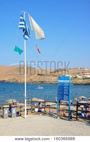 PANORMOS, CRETE - SEPTEMBER 15, 2016 - Greek flag and information board on the edge of the beach with views towards the rocky coastline Panormos Crete Greece Europe, September 15, 2016.